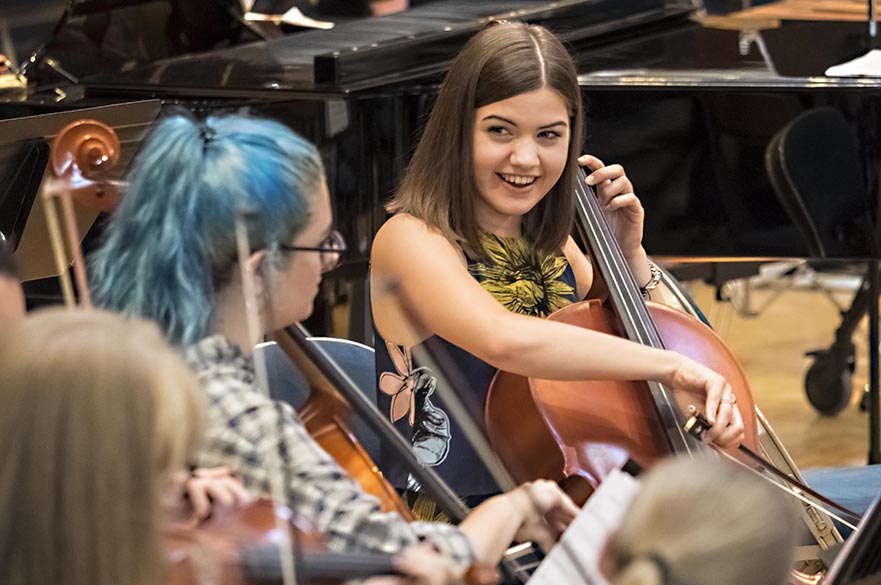 Female students playing the cello in rehearsal.