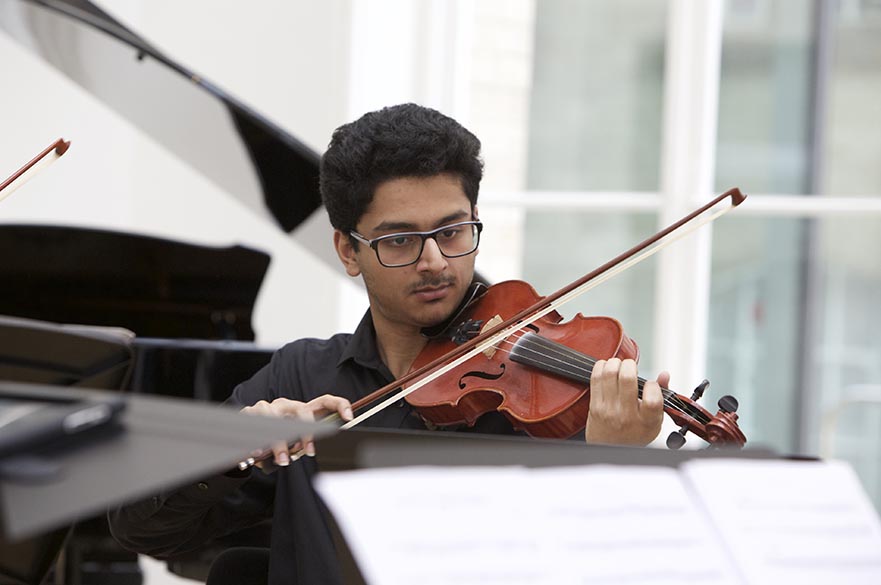 A male student playing a violin.