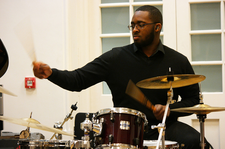 A male student playing the drum kit.