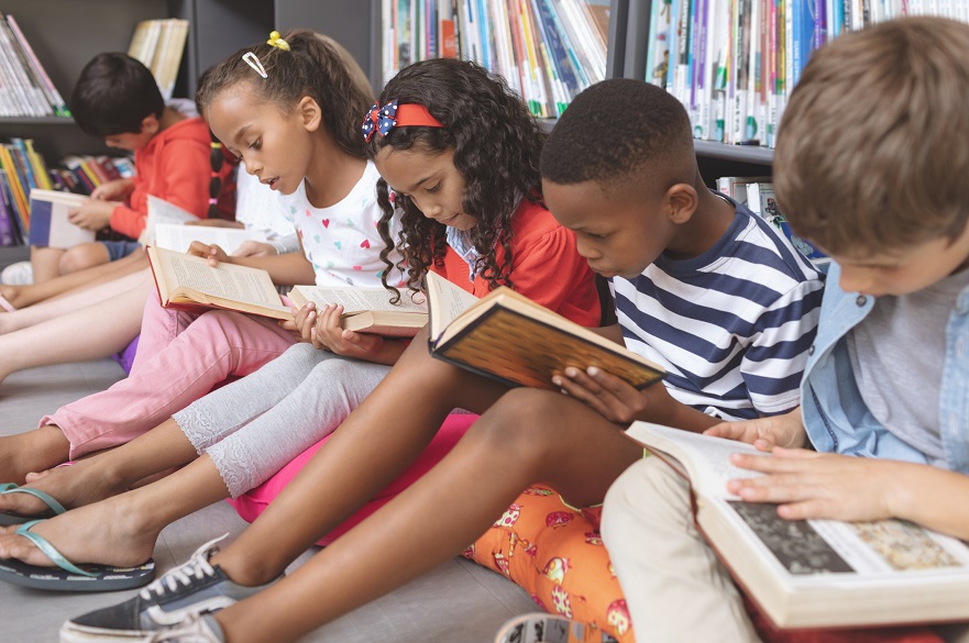 Five children sitting reading books