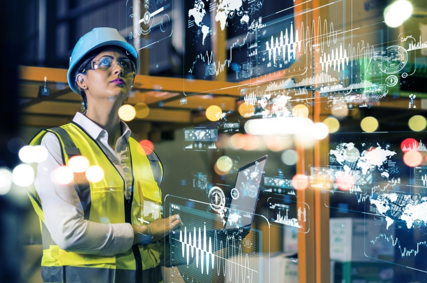 Woman in hard hat had and high vis looking at data