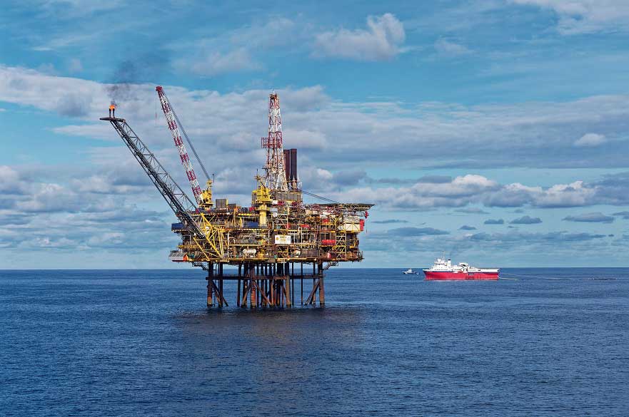 Shell oil rig in the middle of the ocean with a blue sky