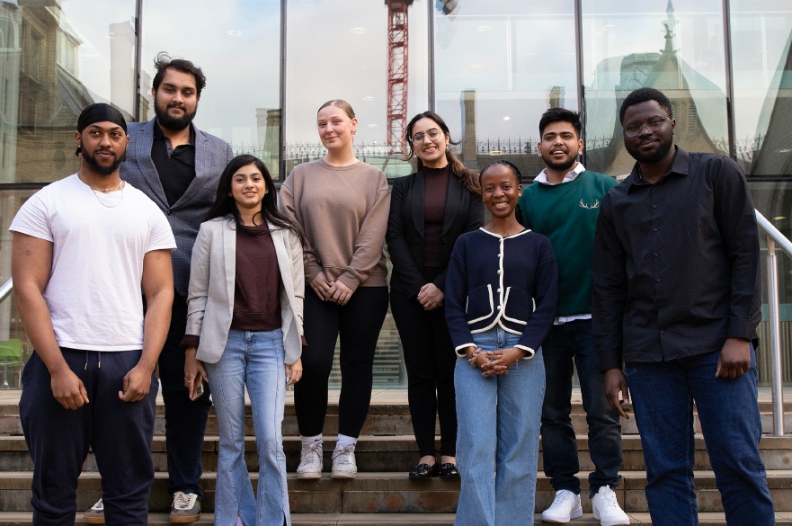 Group of students outside on steps smiling at camera