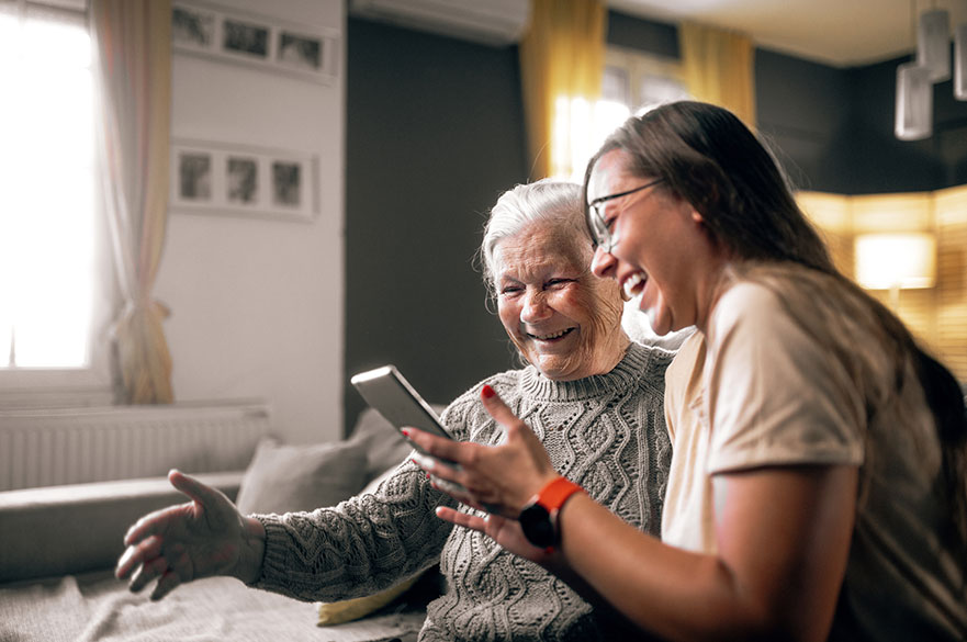 An older woman and younger woman using a mobile phone and smiling