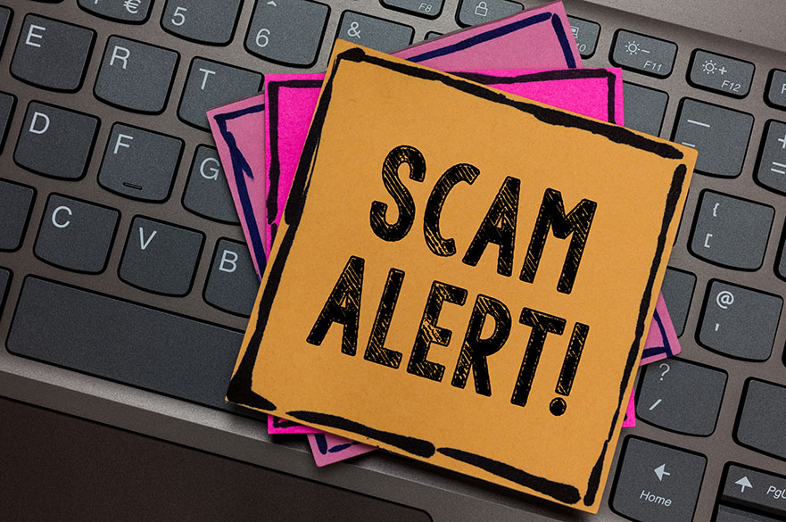 Post it notes on a keyboard with scam alert written on them
