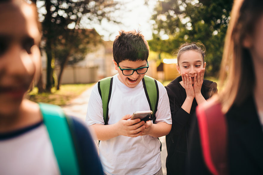 Young boy and girl laughing at a phone screen