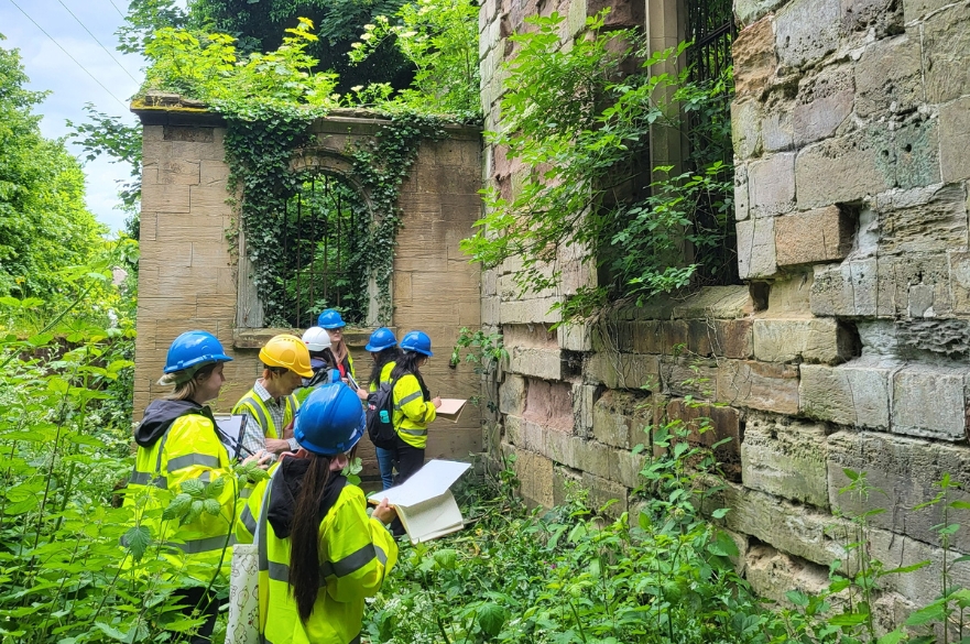 Architecture students wearing high viz's walking around the ruins of an old church.