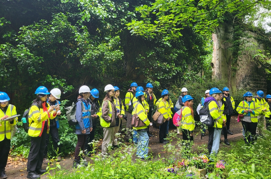 Architecture students wearing high viz's walking around the ruins of an old church.