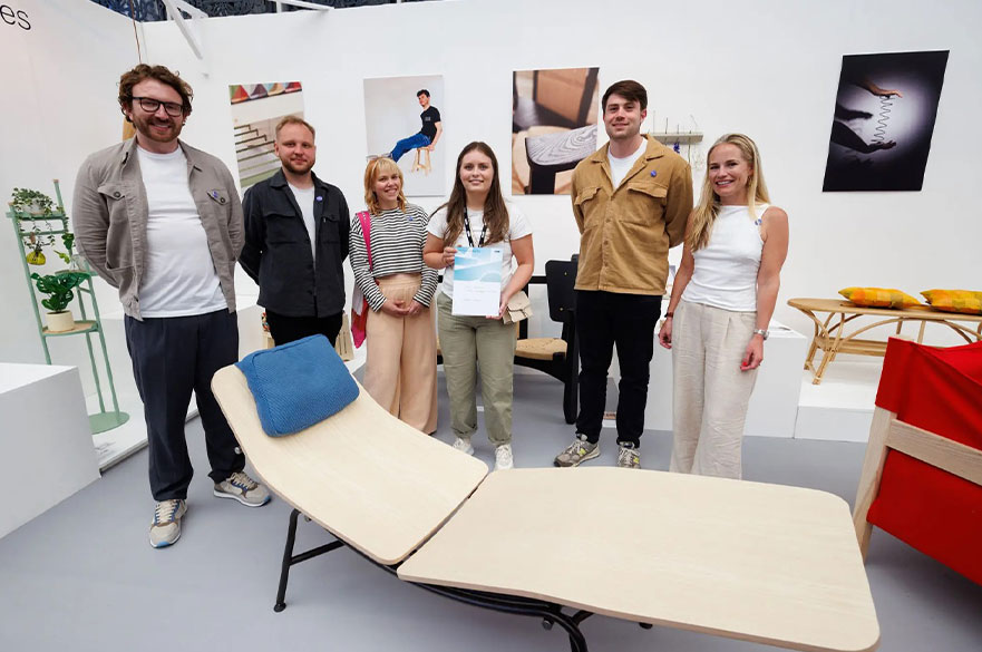 NTU students standing next to her design and posing for the camera with her award and industry experts.