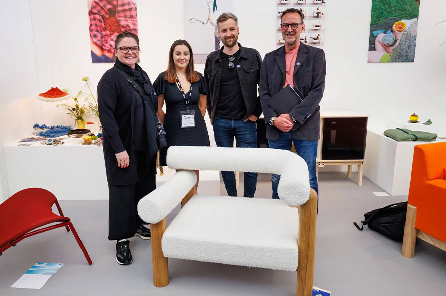 NTU student standing next to her design and posing for the camera with her award and industry experts.
