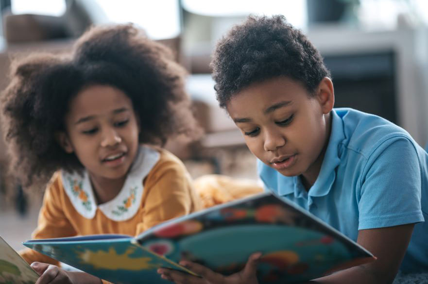 Two primary age children on the floor reading a book