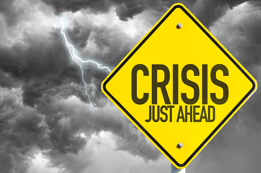 Yellow crisis ahead sign against a grey sky