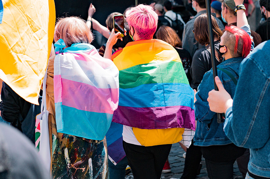 Back view of people with LGBT and Trans flags protest on the street