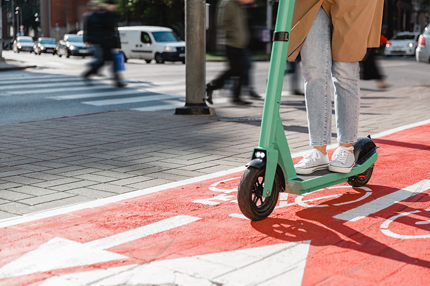 Legs of a woman on an e-scooter crossing a road