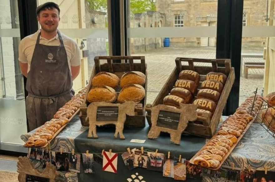 Jordan Young standing next to baked items, including bread and pastry