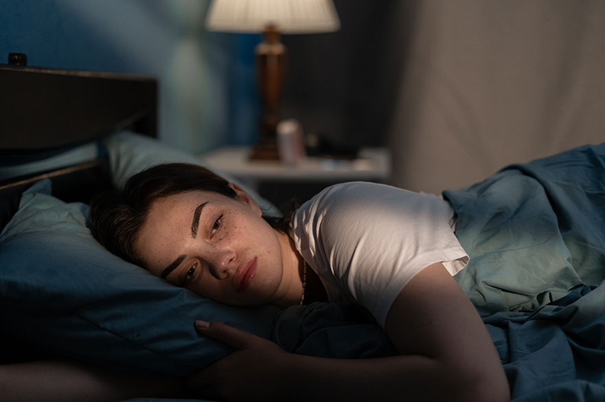 woman lying awake in bed looking worried