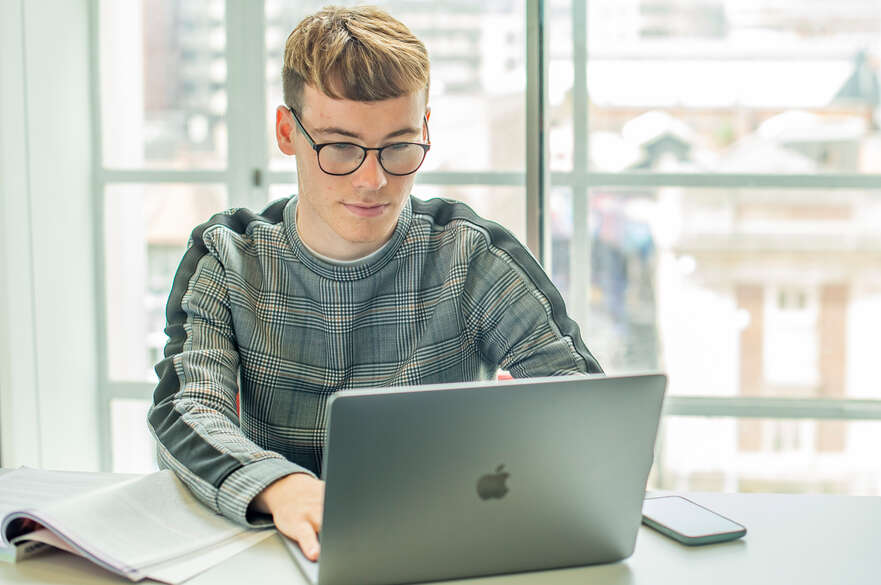 Student sitting at a table using a laptop