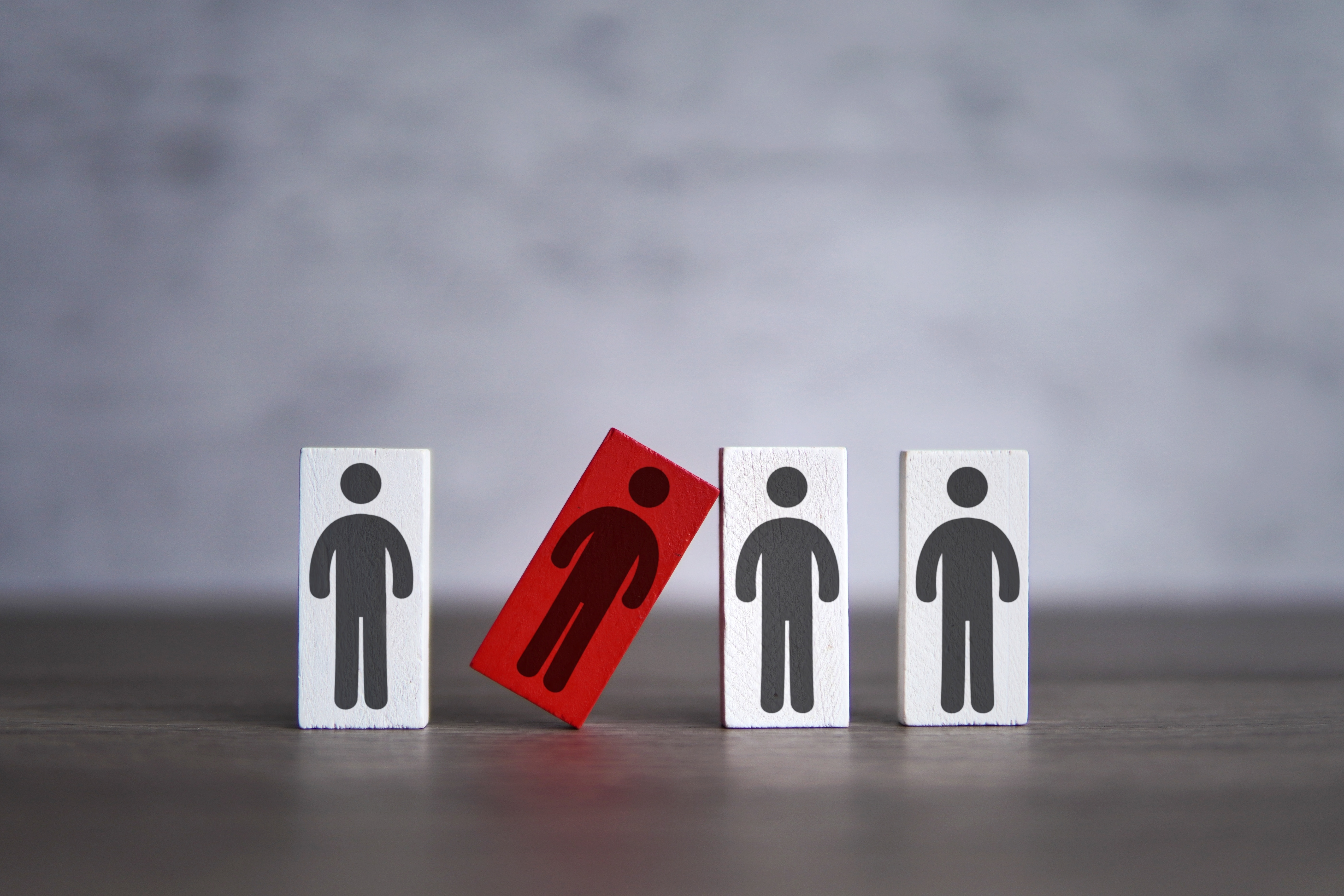 Image showing 4 figures, with one in a different colour and falling over to represent difficulties/exclusion