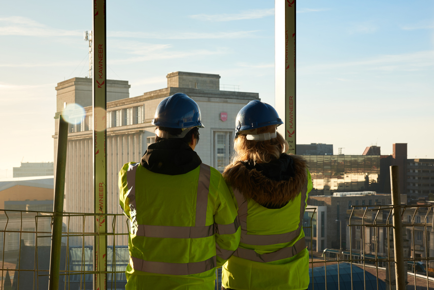 Students in a construction site looking into the city