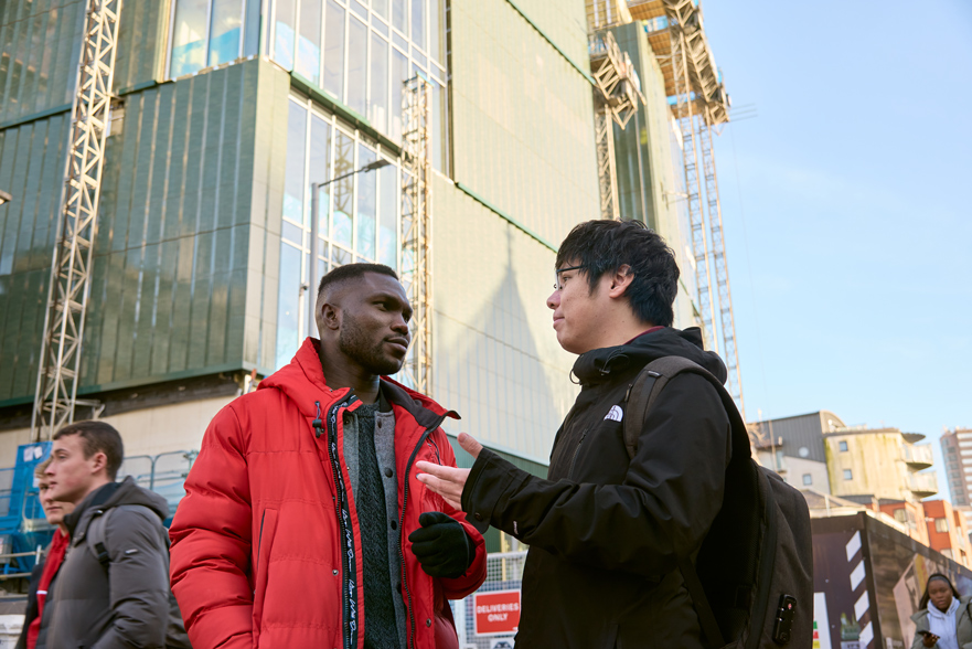 Students walking and smiling in-front of construction site