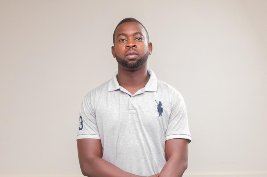 Man stood with arms crossed on plain background