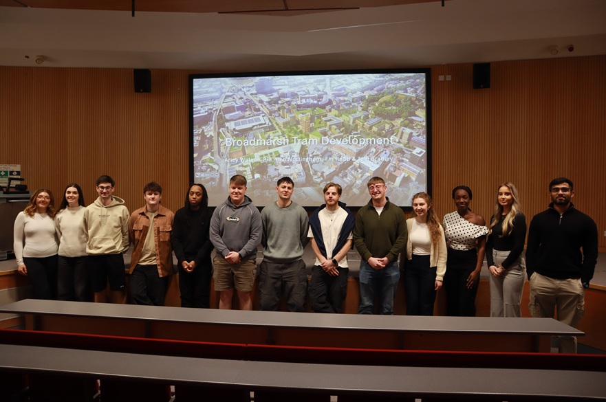 A group of students pose for a photograph at an end of project event with academics and other stakeholders.