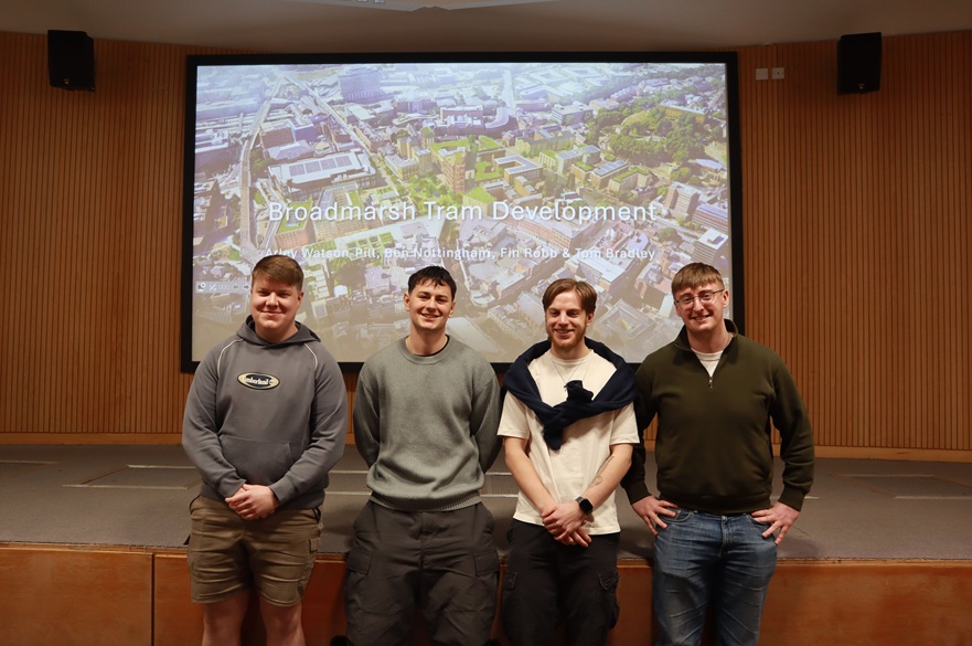 Four students in front of a presentation on screen.