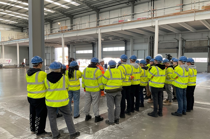A group of people wearing high-vis jackets and hardhats standing inside a distribution unit on a construction site