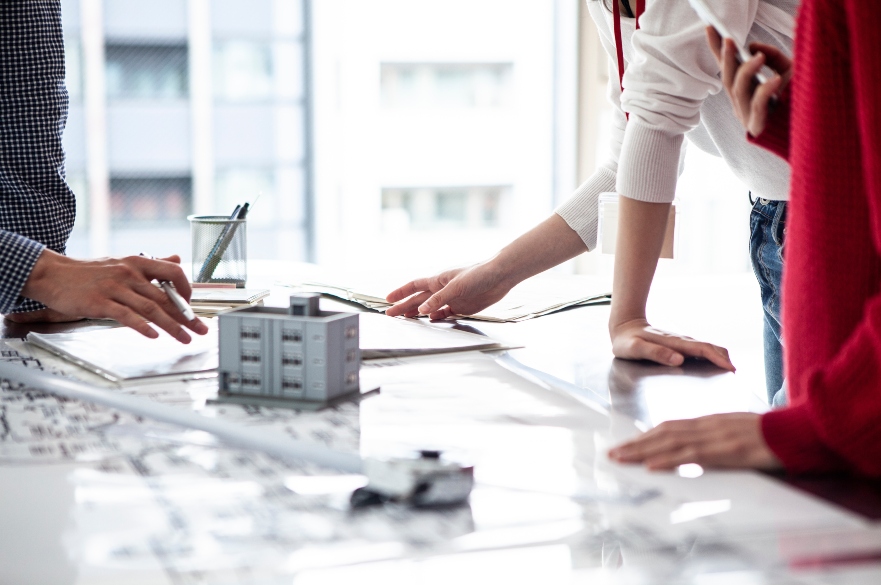 three people looking at building plans around table