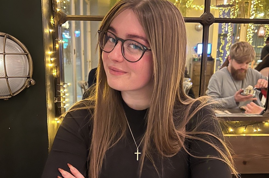 A person in a restaurant. They are smiling looking at the camera.