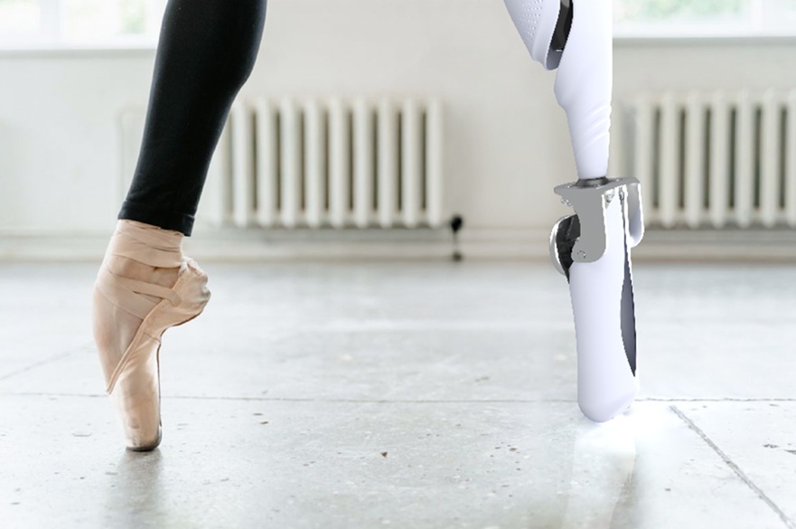 A close-up of a ballet dancer's feet on tiptoe. One foot is wearing a ballet shoe. The other foot is a prosthetic foot.