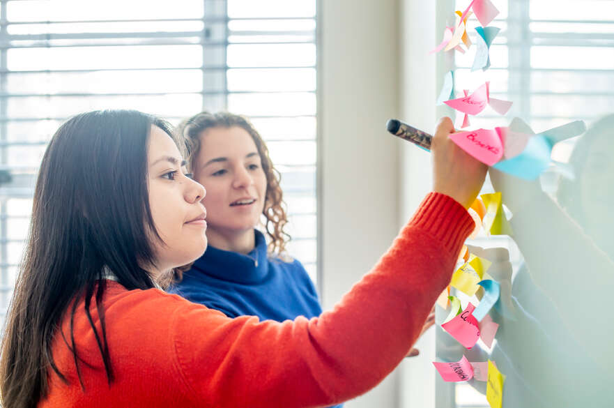 Two students writing on a board