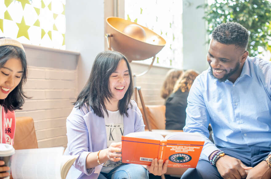 Three students looking at a book