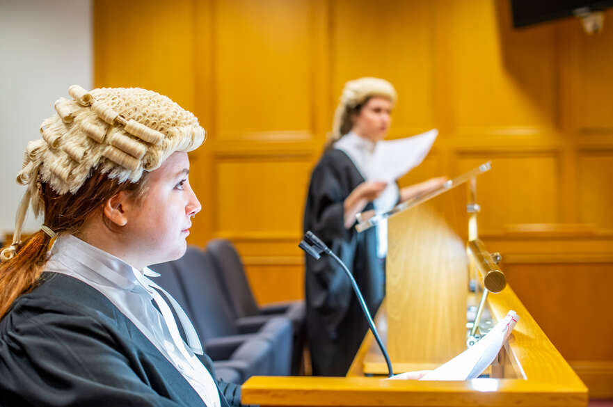 Students performing in courtroom with papers