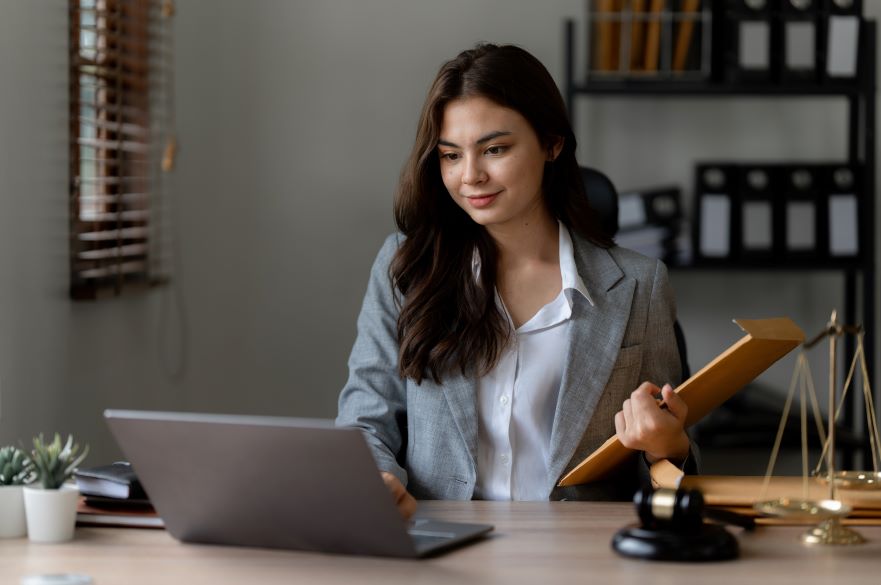 Female Lawyer Looking at Laptop with Papers