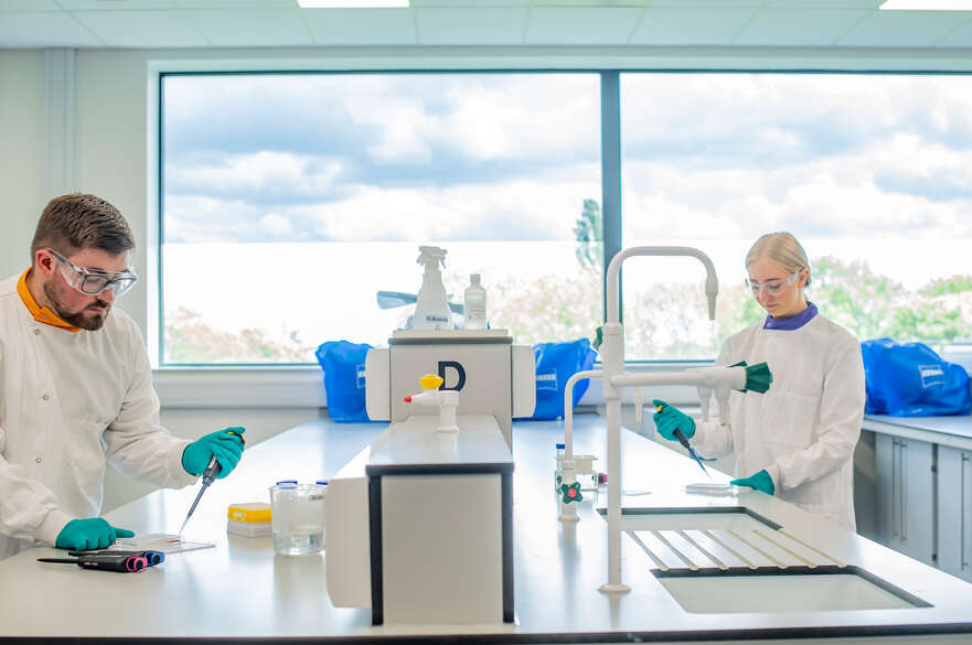 Two students in a lab using lab equipment