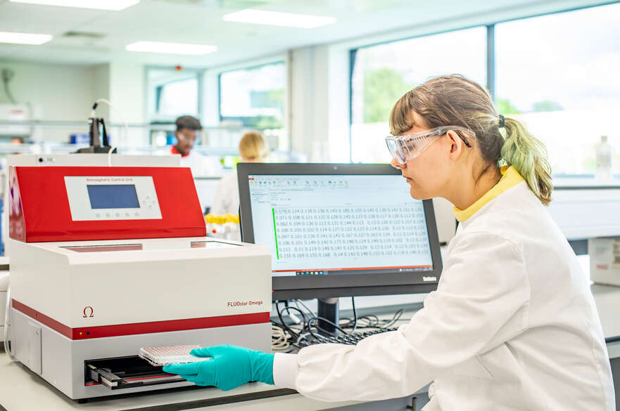Student sat in front of computer and using lab equipment