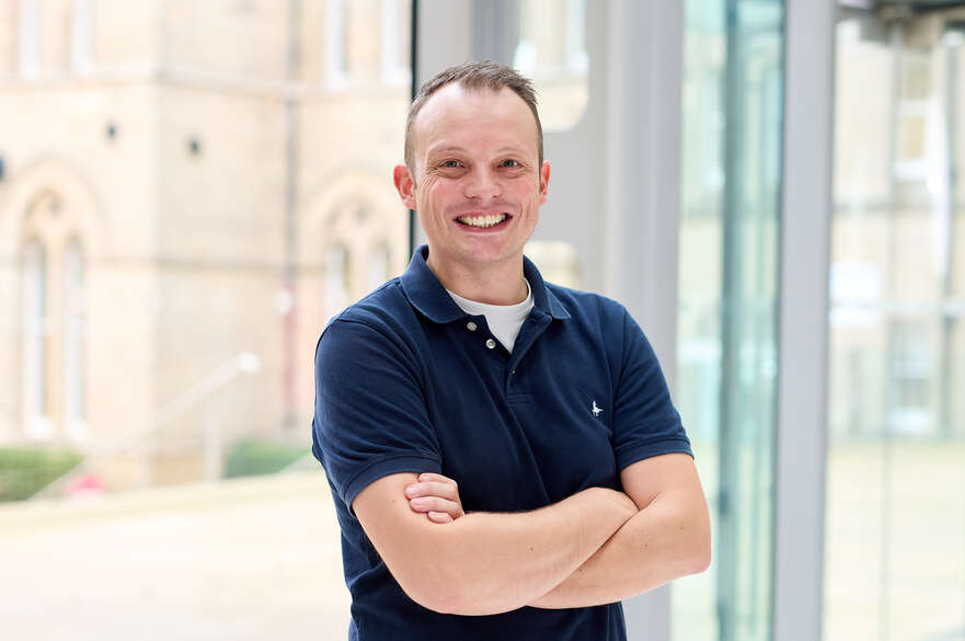 Person in blue shirt, arms crossed, smiling at camera.