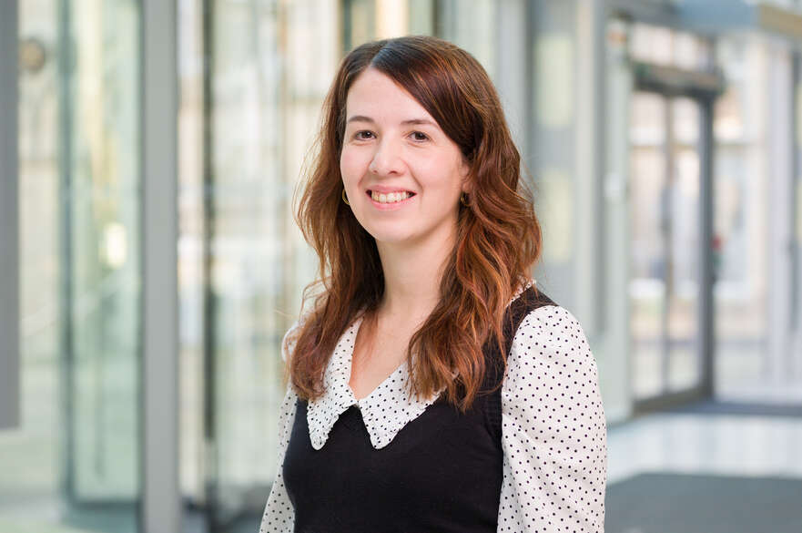 Rachel Handforth stands smiling in front of some glass doors.