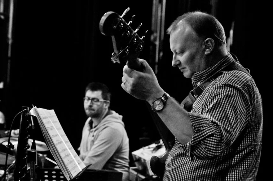 Man holding a bass guitar looking at music sheet.  