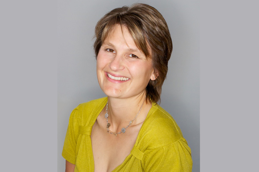 Woman wearing a yellow shirt smiling at the camera