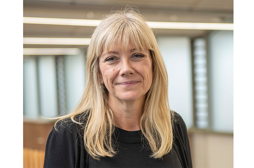 Closeup image of a woman with blonde hair wearing a black shirt with a black jacket