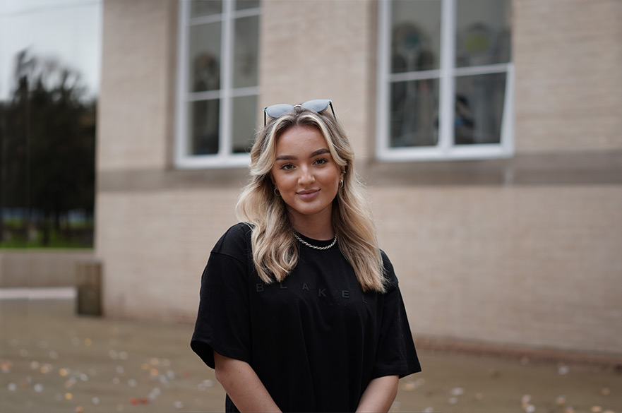 Becca smiling at the camera outside a building