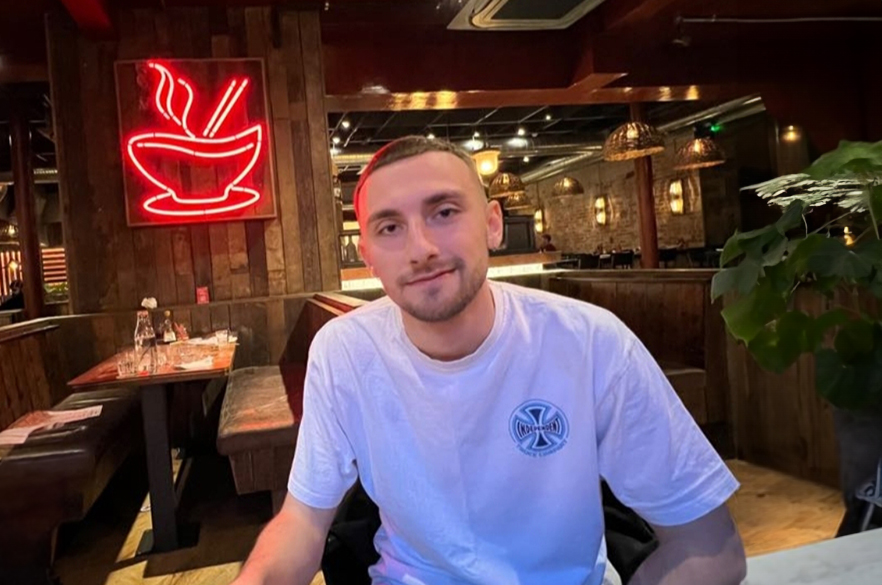 Cavan smiling at the camera inside a restaurant