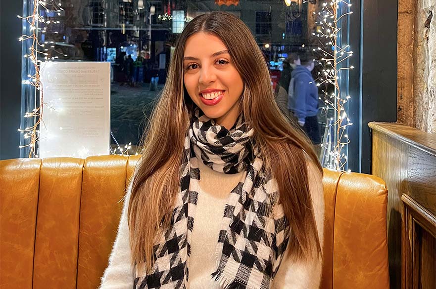 Maria smiling at the camera sitting at a table in a restaurant