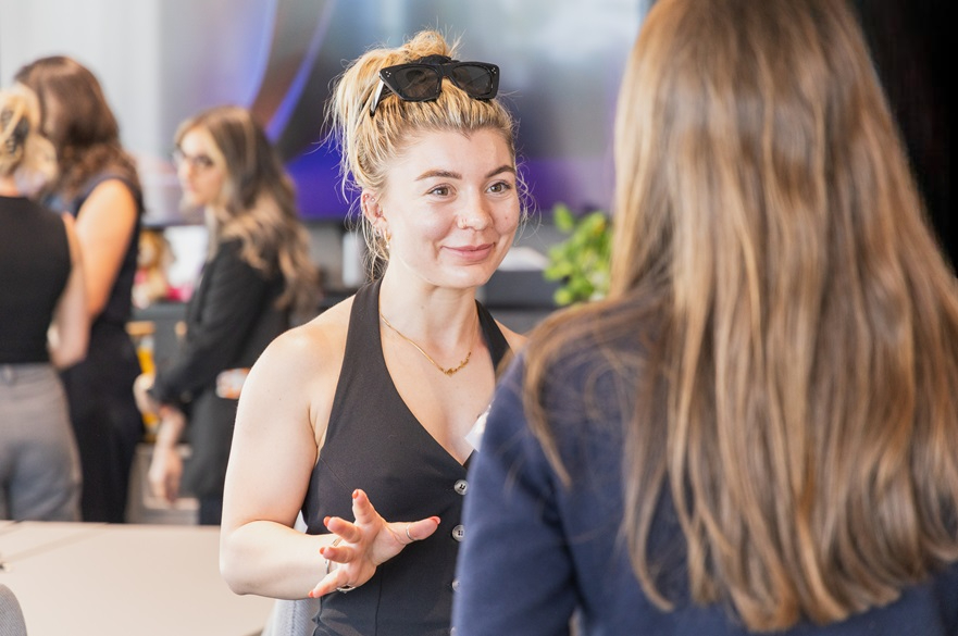Two female students in conversation, pictured at an event.