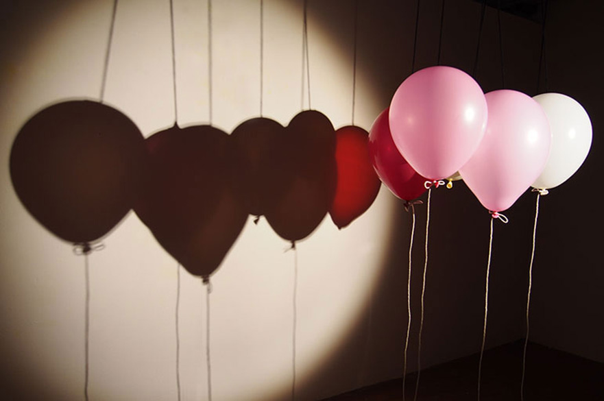 Pink balloons casting shadow on wall