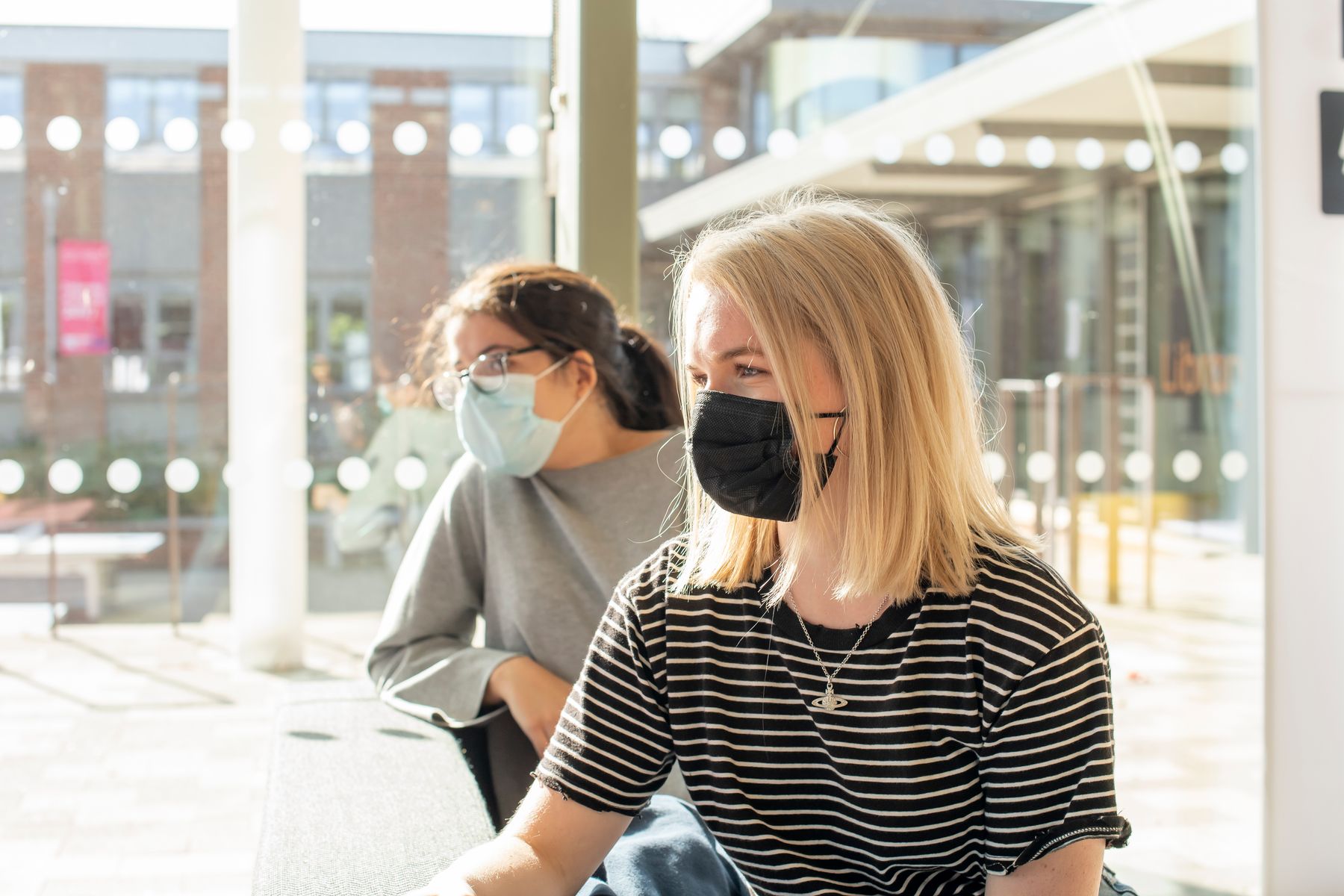 Two students sat at a table wearing face coverings