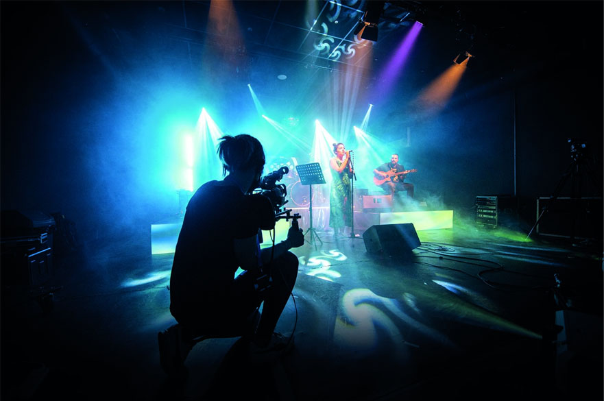 Students performing on a stage while another student films them