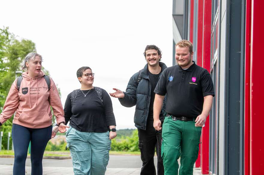 Four mature students walking and chatting together on campus.